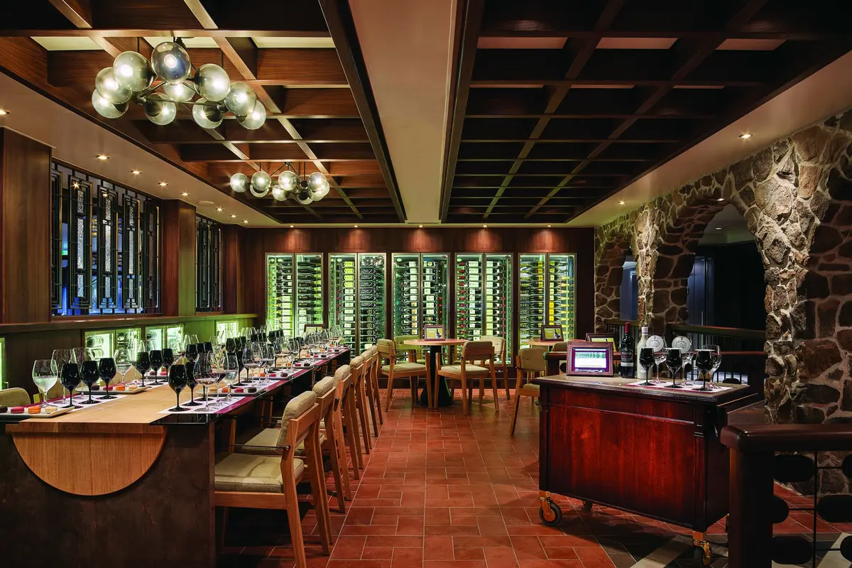 Warm timber shelves and intimate evening seating inside The Cellars Wine Bar on Norwegian Bliss