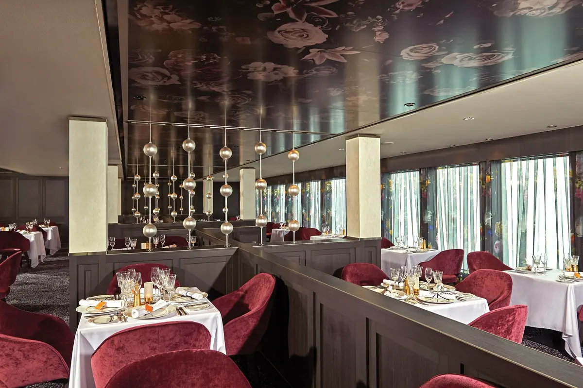 Le Bistro, red velvet chairs and white tablecloths under a painted ceiling