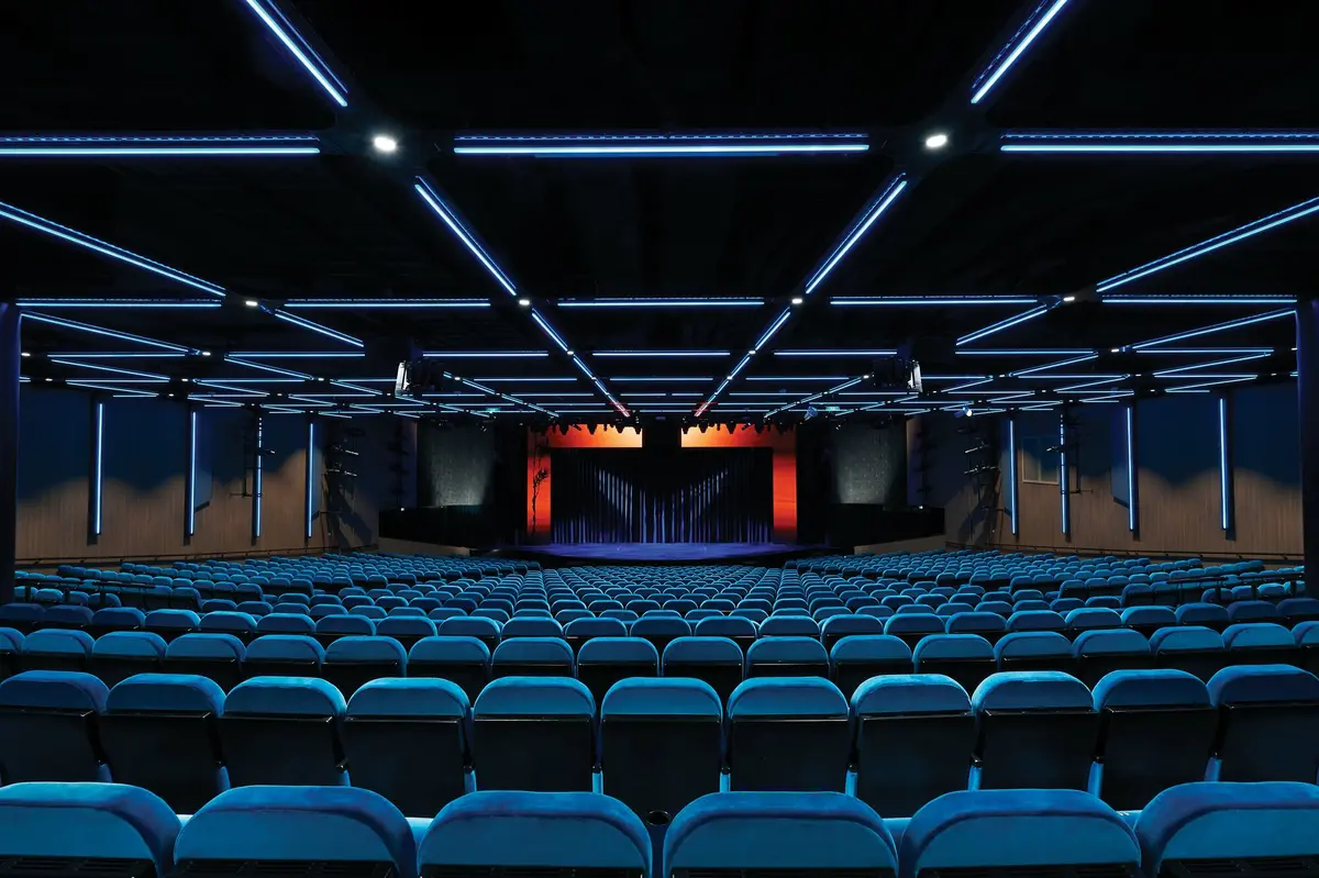 Tiered velvet seating facing the stage inside the Bliss Theatre